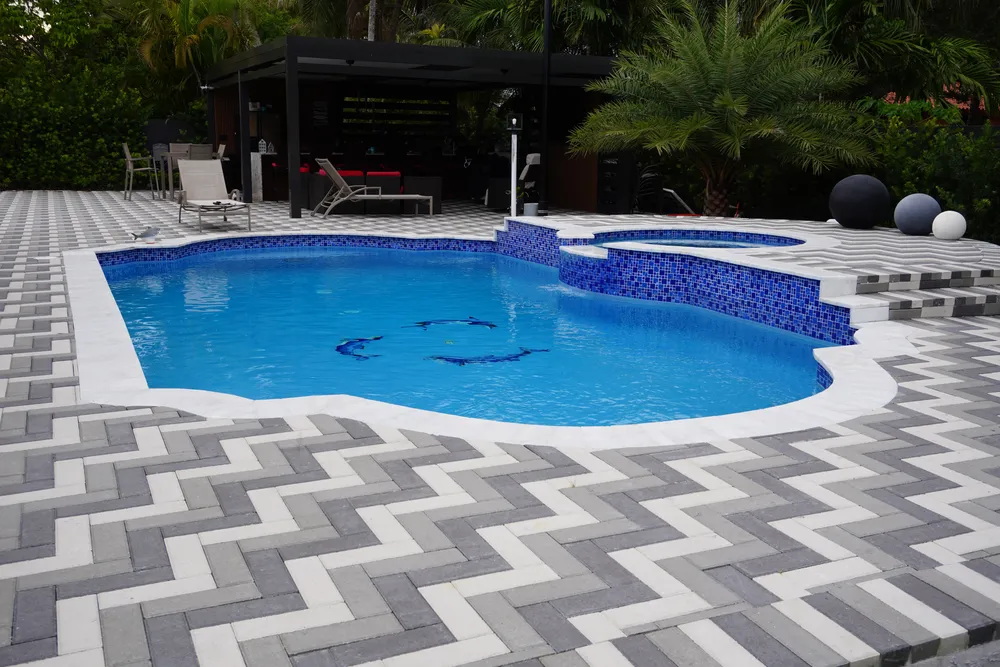 Pool with herringbone paver deck and pergola