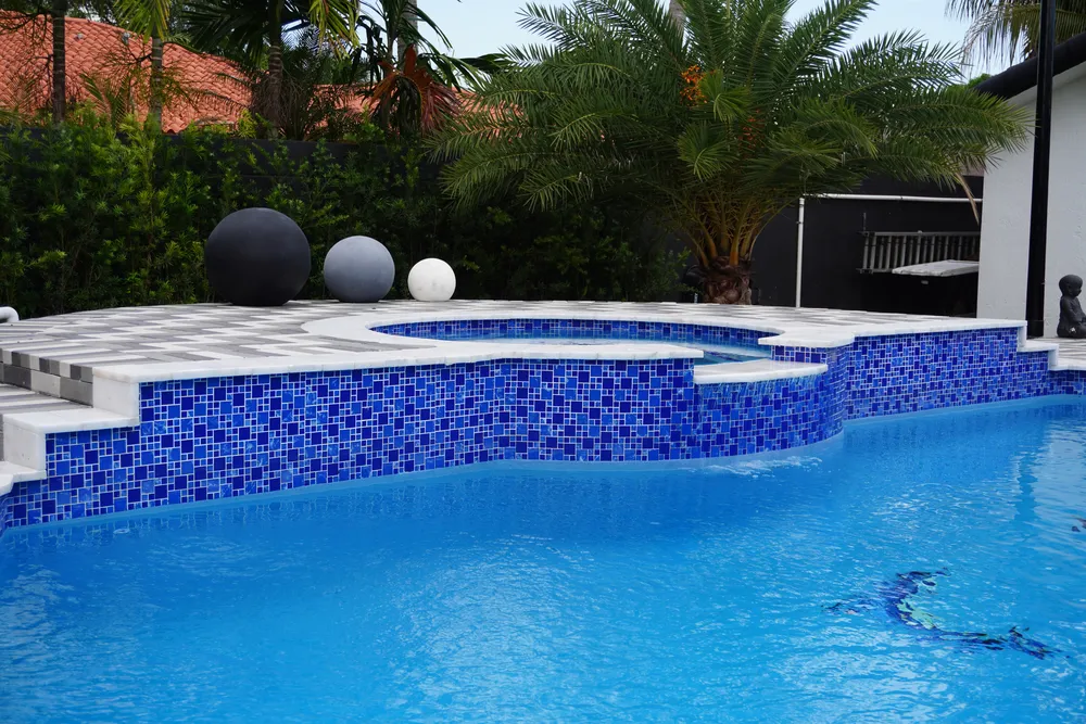 Blue mosaic pool with paver deck