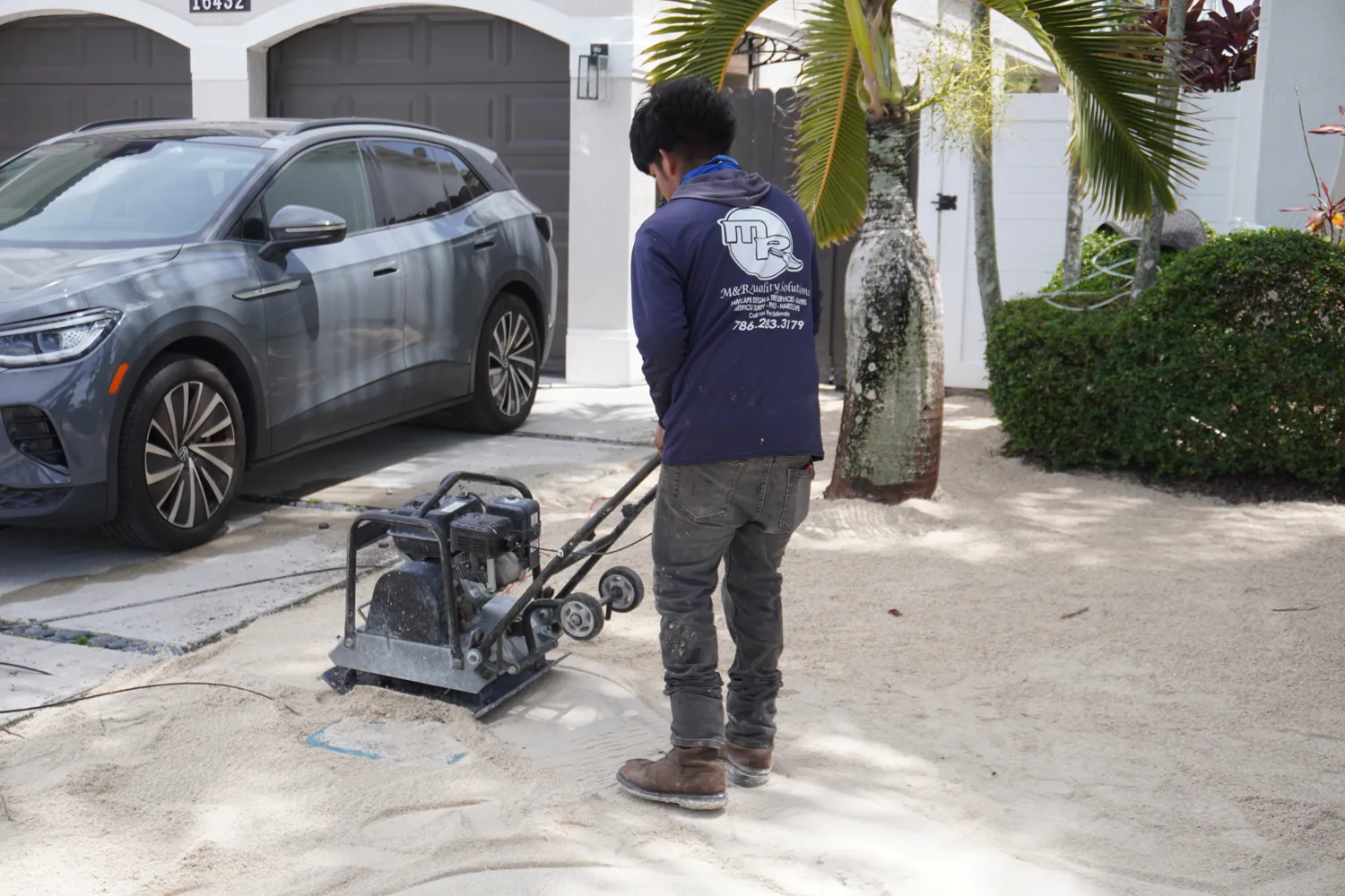M&R Outdoor Living crew running a plate compactor