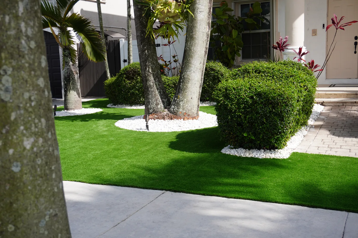 Artificial turf front lawn with palms and hedges in West Kendall by M&R Outdoor Living